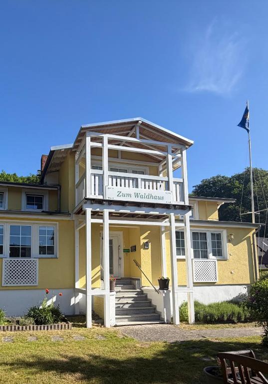 a large yellow building with a balcony on top of it at Waldhaus Sellin in Ostseebad Sellin