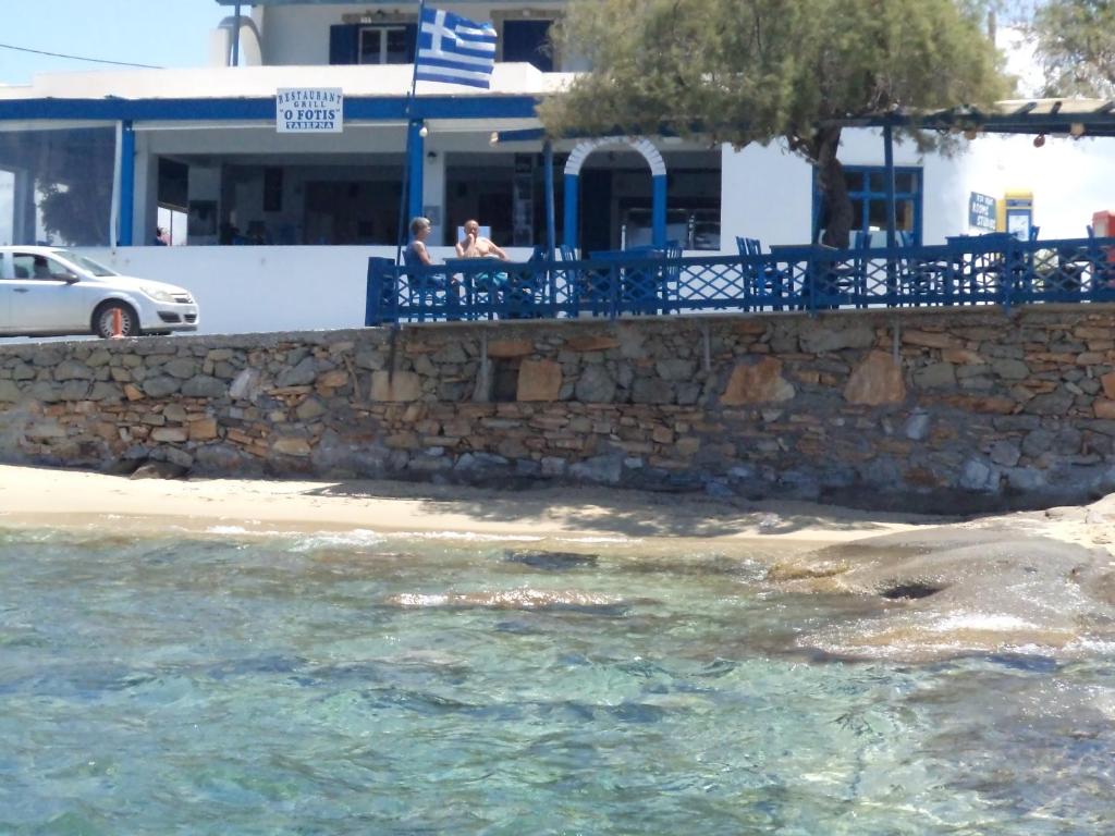 zwei Menschen sitzen an einer Wand neben dem Wasser in der Unterkunft O Fotis in Agios Prokopios