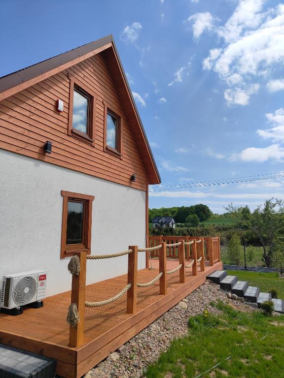 a house with a wooden deck next to a yard at MAKS HOUSE KASZUBY Balia Lake and Forest Retreat in Przewóz