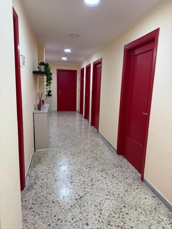 a hallway with red doors and a tile floor at Pompei Sanctuary rooms in Pompei