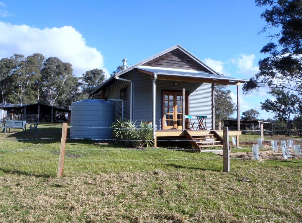una pequeña casa azul con porche y patio en Woodenbong Bed and Breakfast, en Woodenbong