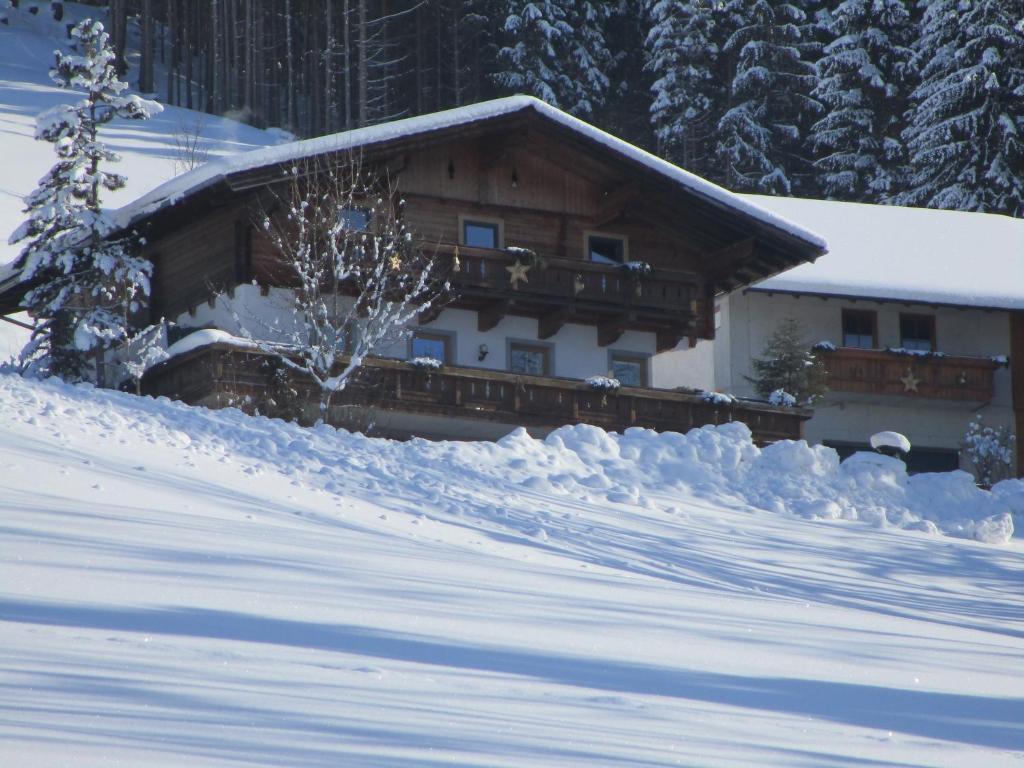 a house covered in snow with a pile of snow at Ferienwohnung Oberbachhof in Sankt Johann im Pongau