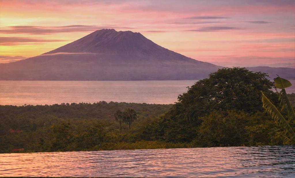 a mountain in the distance with a body of water at EDEN Private Pool Suites and Panoramic Agung View - ADULT ONLY in Nusa Penida