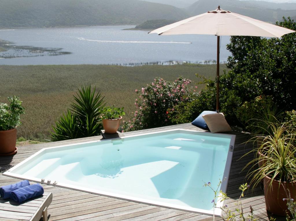una piscina en una terraza con sombrilla en Interlaken Guest House, en Wilderness