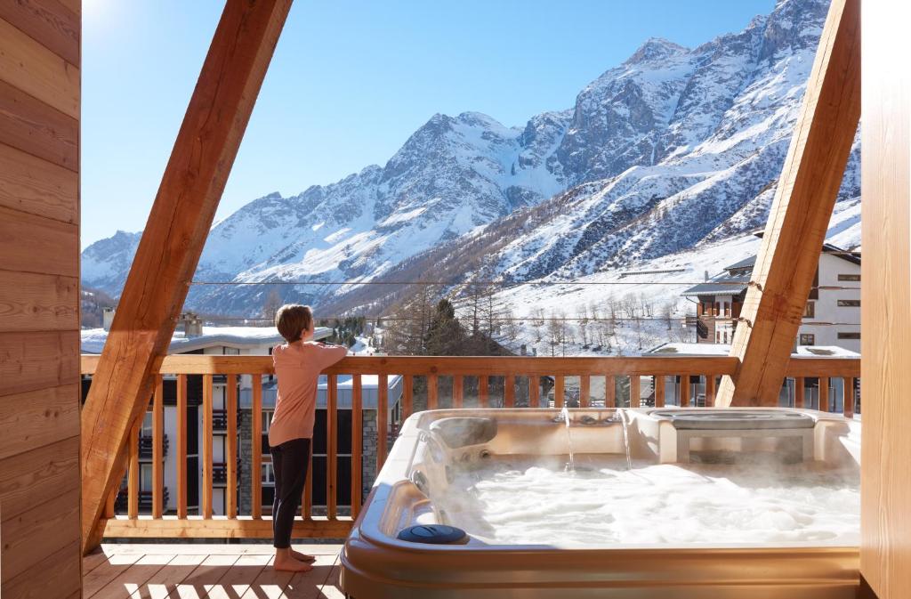 a person standing on a balcony looking out at the mountains at Aux Pieds du Roi - Suite & Spa in Breuil-Cervinia