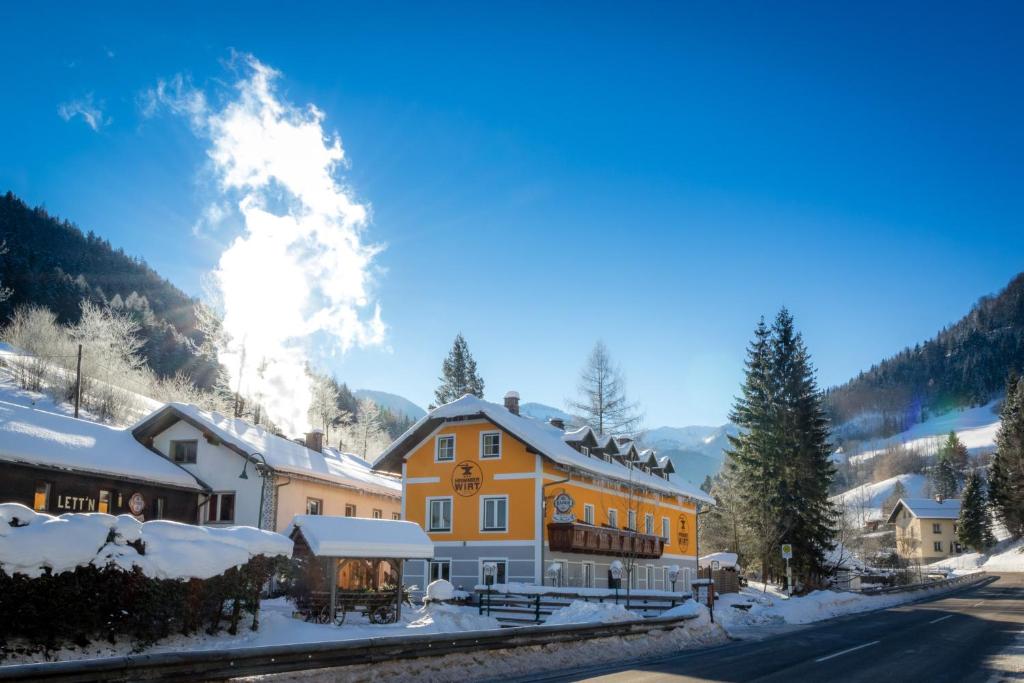 a large yellow building with snow on the ground at Gasthof zum Hammer in Göstling an der Ybbs