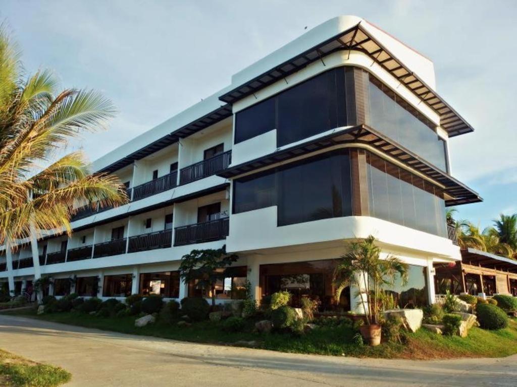 a large building with palm trees in front of it at Jamont Hotel in Sipalay