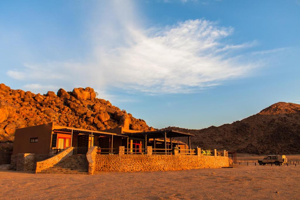 a building in the middle of a desert with a mountain at Greenfire Desert Lodge in Maltahöhe
