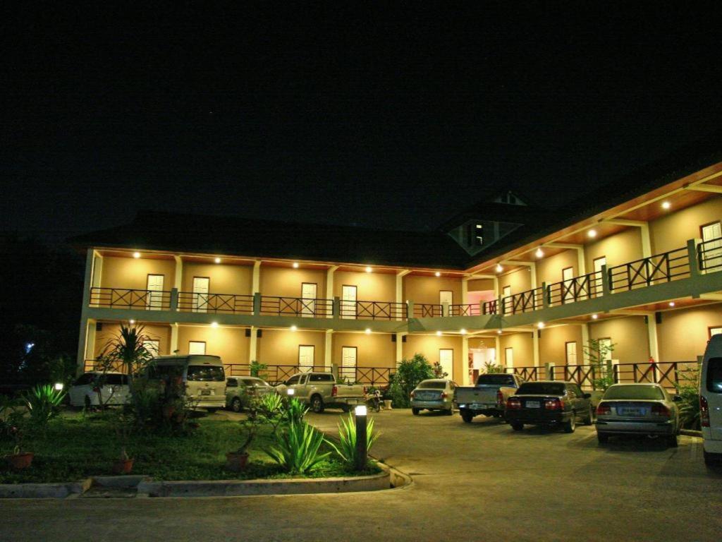 a hotel with cars parked in a parking lot at night at Baan Chomphu in Prachuap Khiri Khan