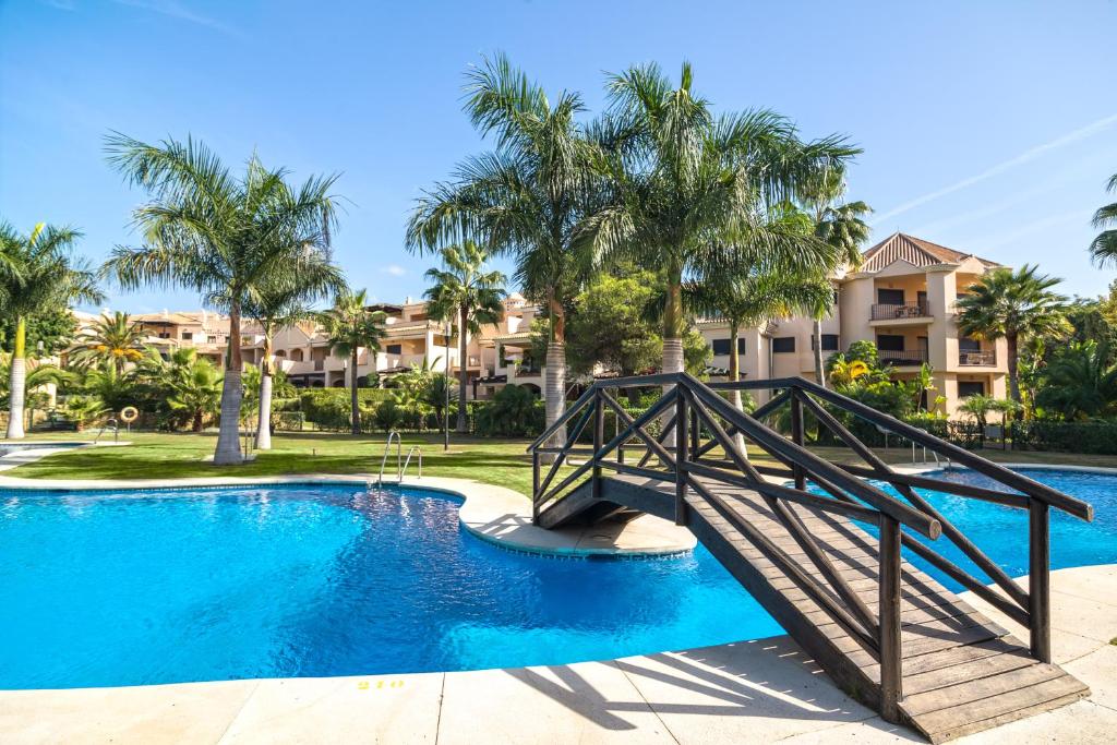 a bridge over a swimming pool with palm trees at Mimosas Suites Banús in Marbella