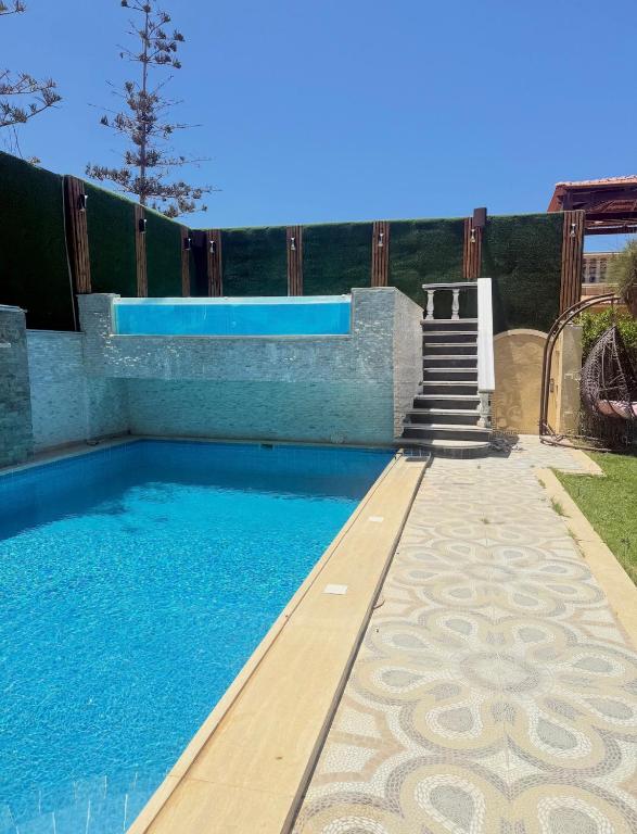 a swimming pool with a staircase leading to a house at Alshrooq Village 97 in Borg El Arab