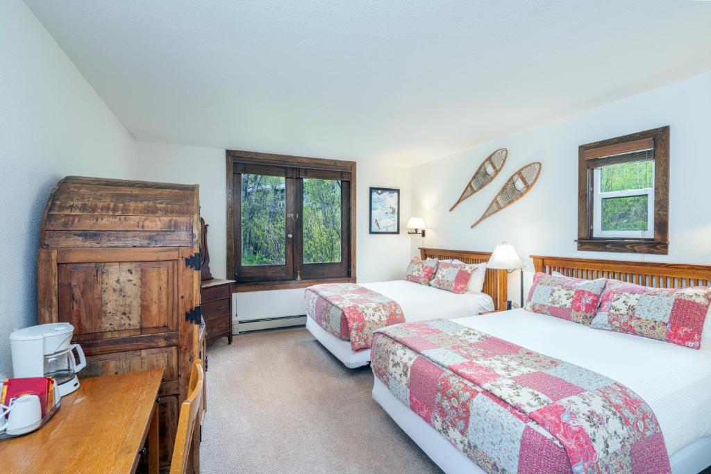 a bedroom with two beds and a desk and two windows at Manitou Lodge 3 by Alpine Lodging Telluride in Telluride