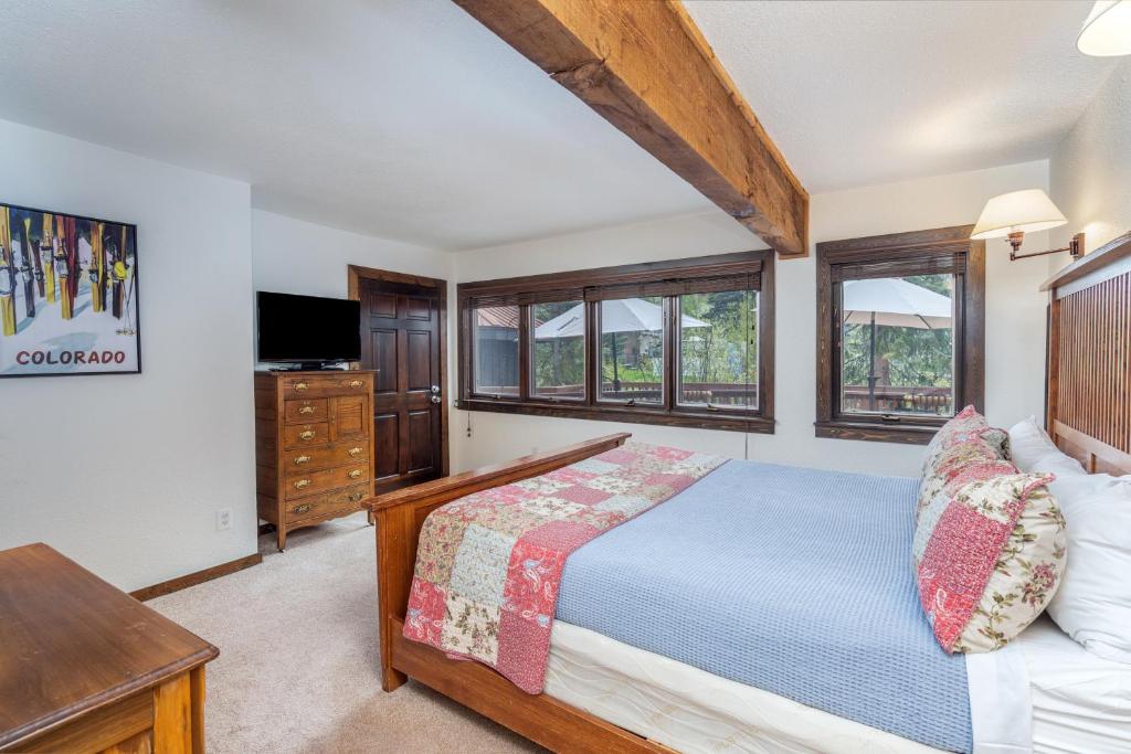 a bedroom with a bed and a tv and windows at Manitou Lodge 4 by Alpine Lodging Telluride in Telluride