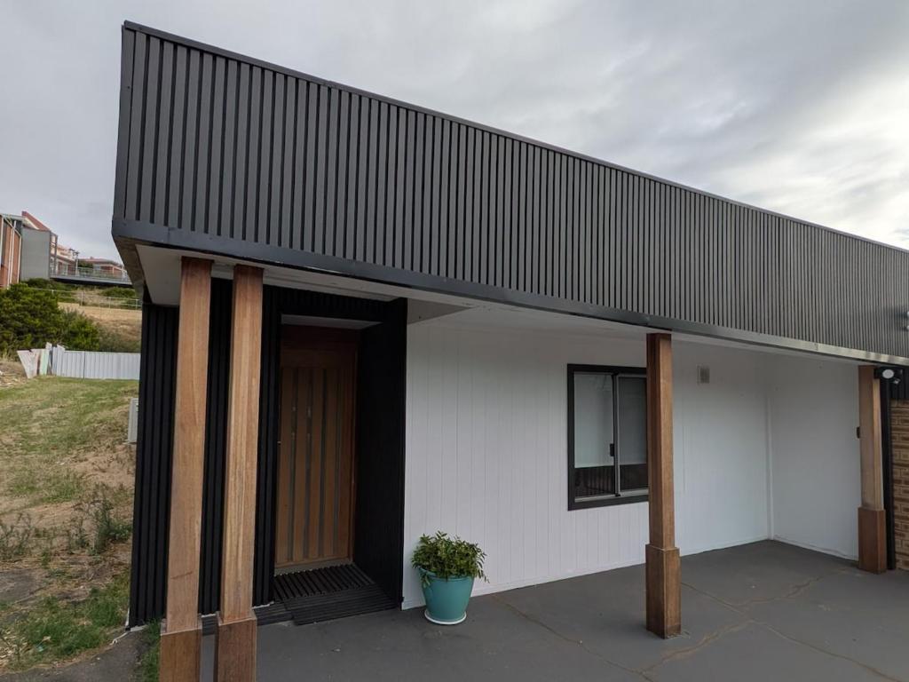 a white house with a black roof and a potted plant at Private Coastal Sanctuary Beachside Escape in Bunbury