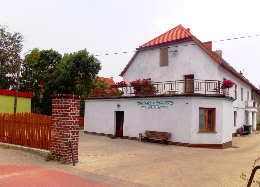 a white building with a bench in front of it at Pokoje u Doroty in Kurowice