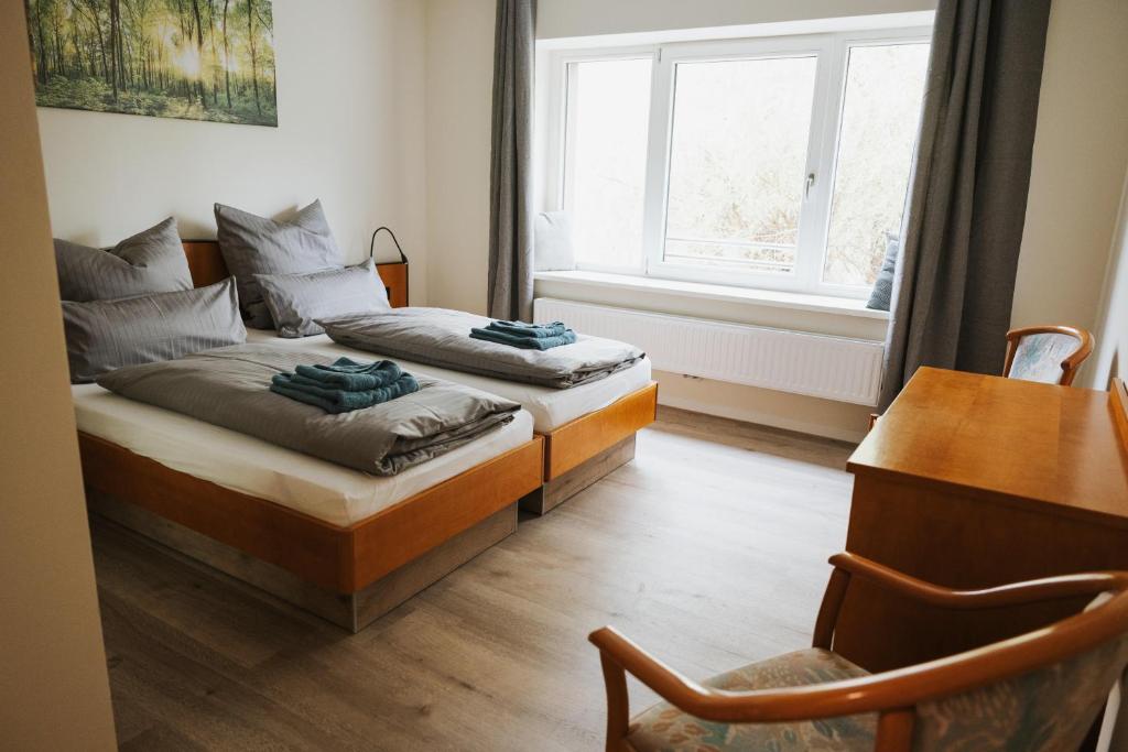 a bedroom with two beds and a desk and a window at Pension Altes Schulhaus in Leuna