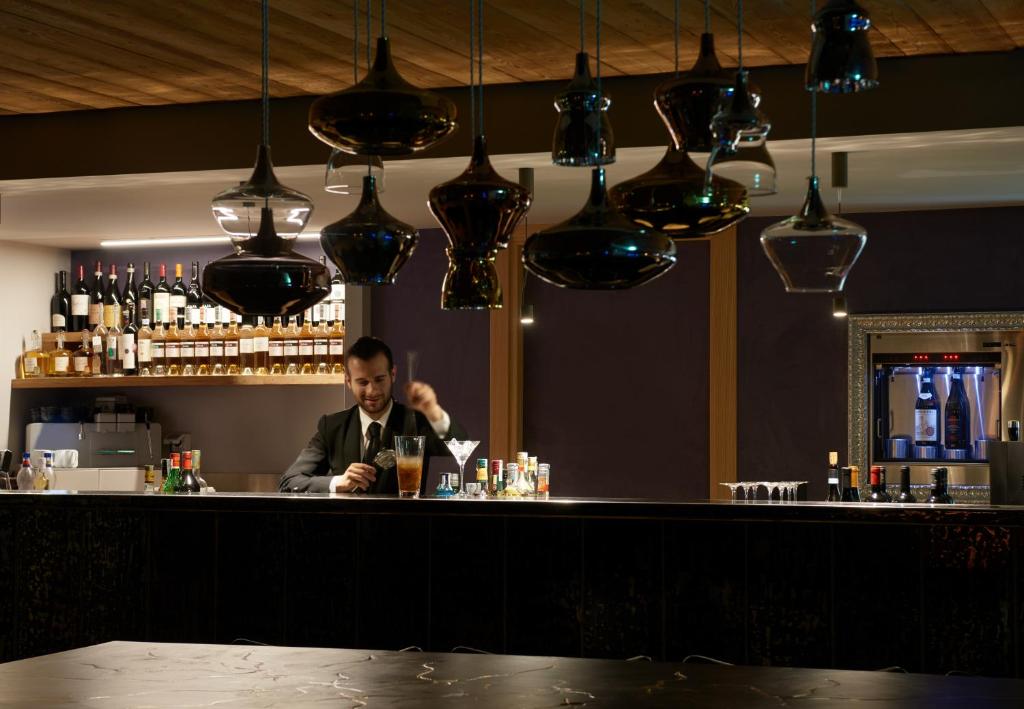 a man sitting at a bar making a drink at Aux Pieds du Roi - Suite & Spa in Breuil-Cervinia