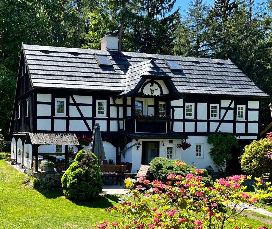 a black and white house with flowers in the yard at Hájenka Sněžník in Sněžnik