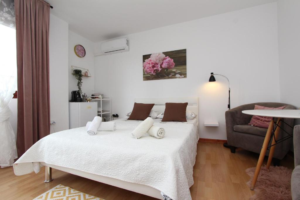 a white bedroom with a bed and a chair at Rooms and Studio Salvi in Rovinj