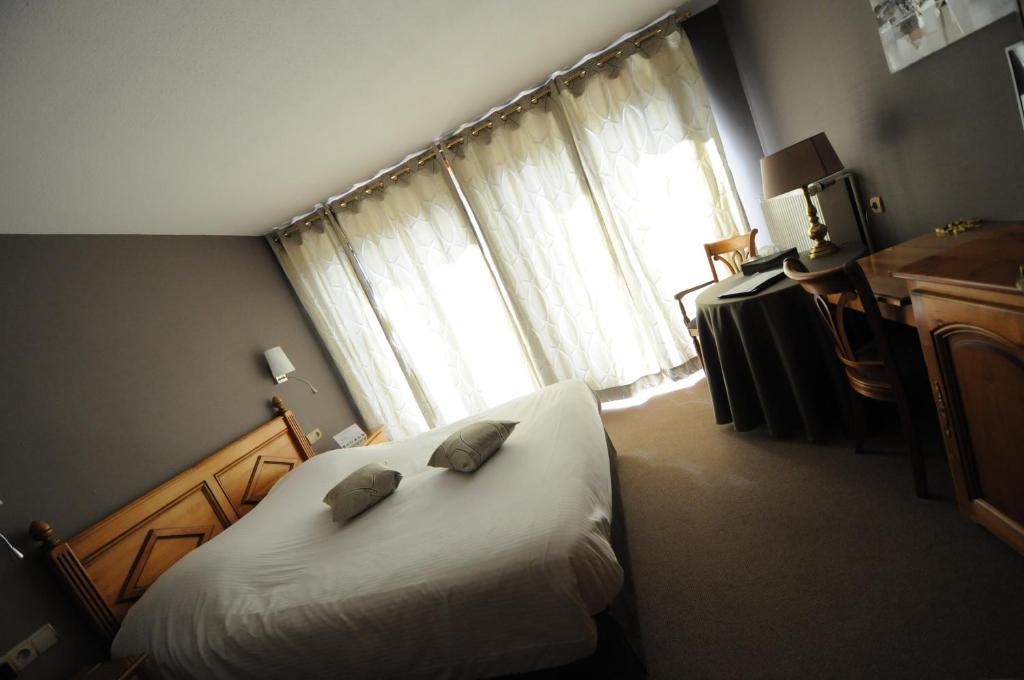ein Schlafzimmer mit einem Bett mit zwei Kissen darauf in der Unterkunft Logis Hotel Restaurant Au Boeuf Rouge in Niederschaeffolsheim