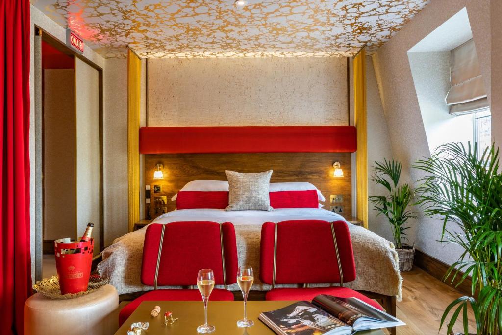 a bedroom with a large bed with red chairs at The Megaro Hotel - Kings Cross St Pancras, London in London