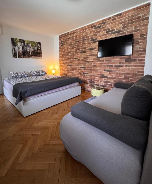 a bedroom with two beds and a brick wall at Apartman Lovrić Đakovo in Đakovo
