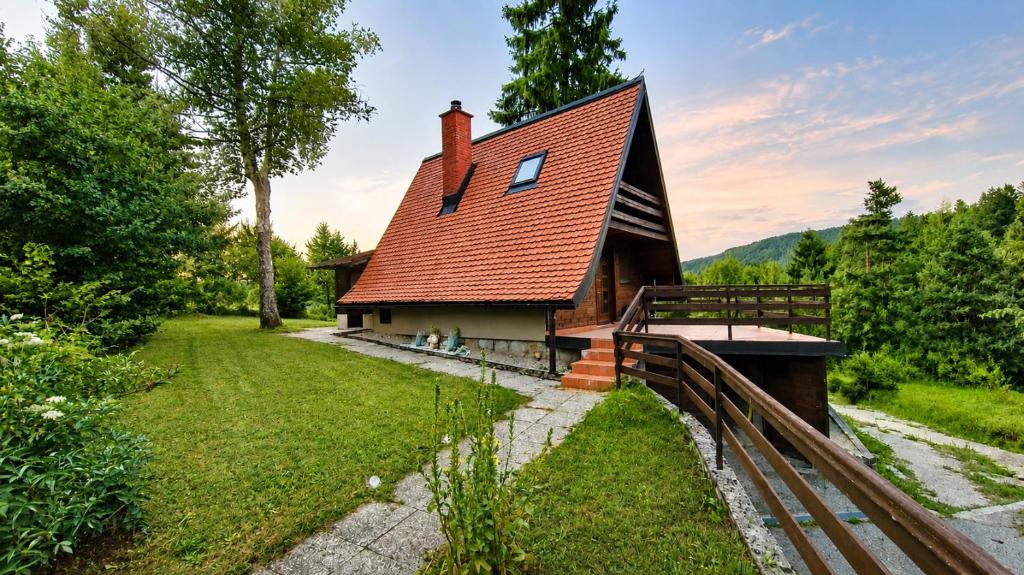 a house with a red roof and a fence at Koča Rakitna Forest Chalet with Sauna in Preserje