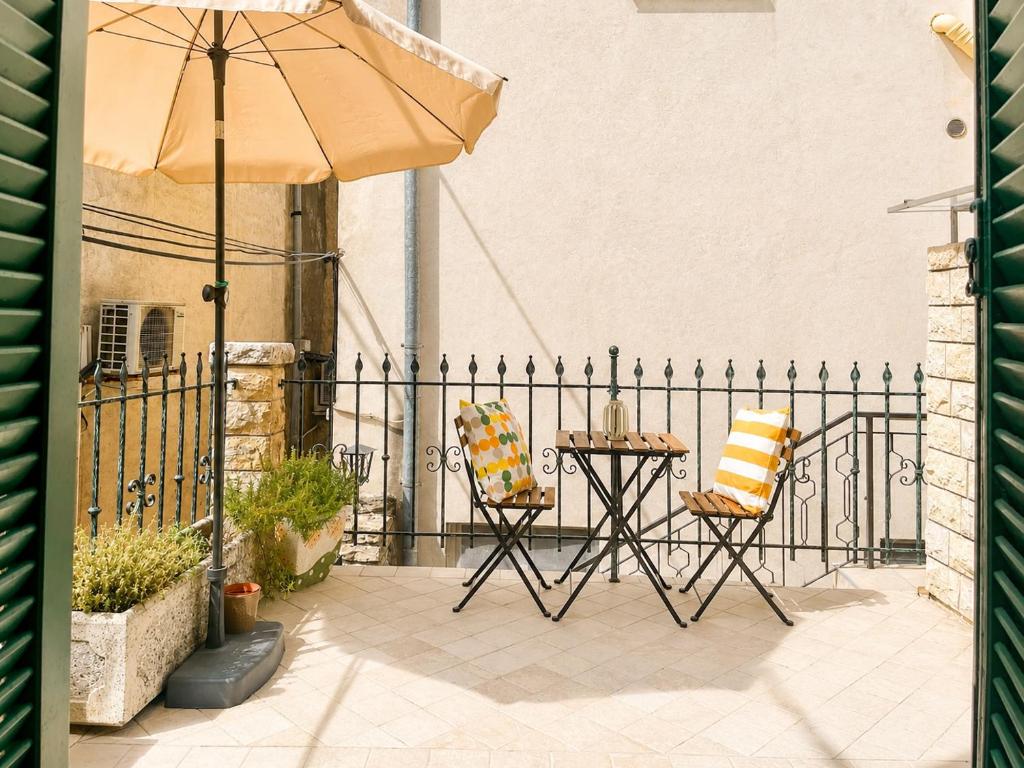 a patio with a table and chairs and an umbrella at Apartment Sulle scale in Piran