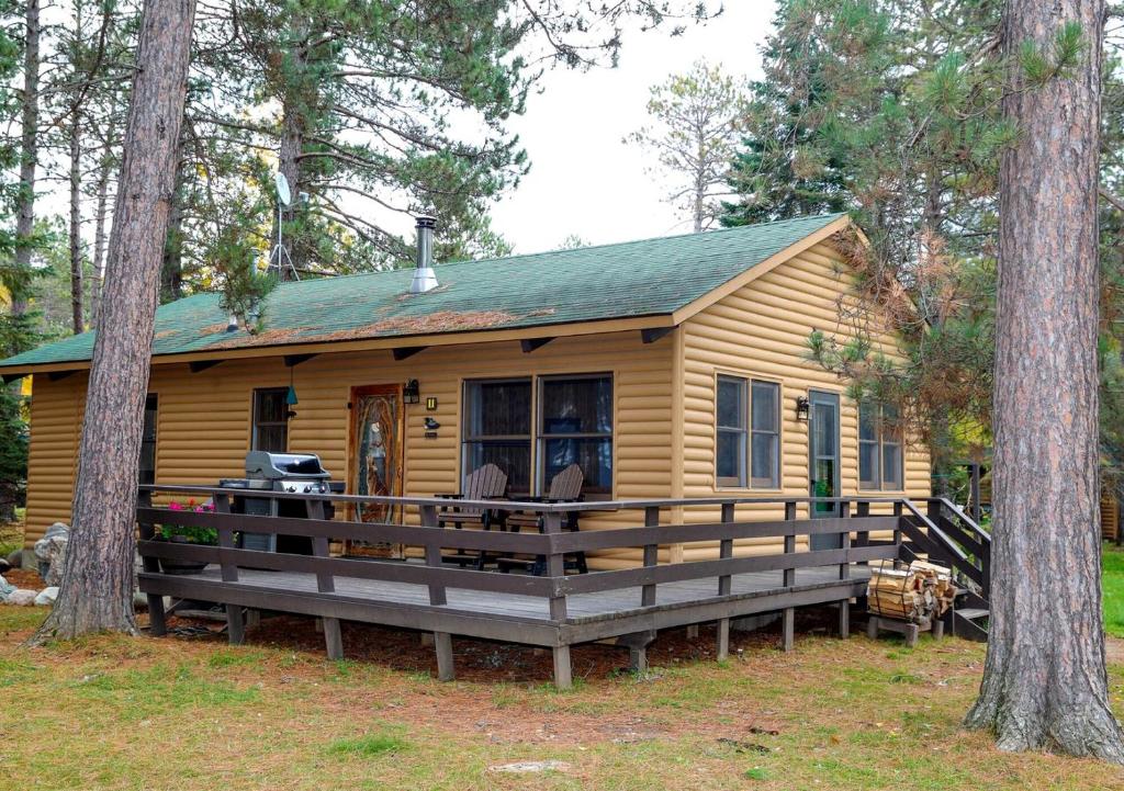 a log cabin in the woods with two trees at Spacious Rustic Cabin with Vaulted Ceilings, Full Kitchen, Fireplace & Large Deck Near Babbitt, Minnesota in Babbitt