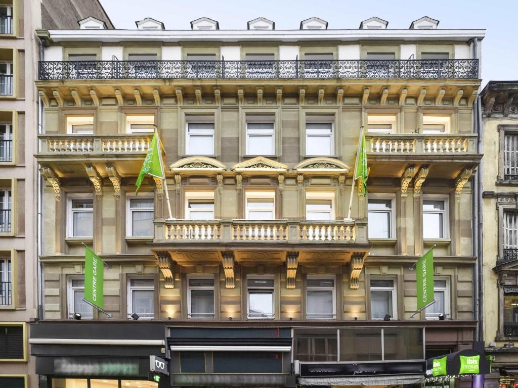 a tall building with green flags in front of it at Ibis Styles Strasbourg Centre Gare in Strasbourg