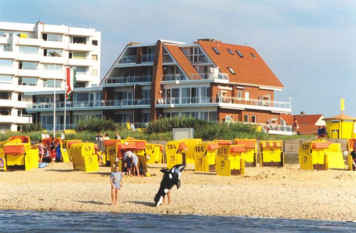 - un enfant et un chien sur la plage avec un bâtiment dans l'établissement Strandhaus Christiansen, à Cuxhaven
