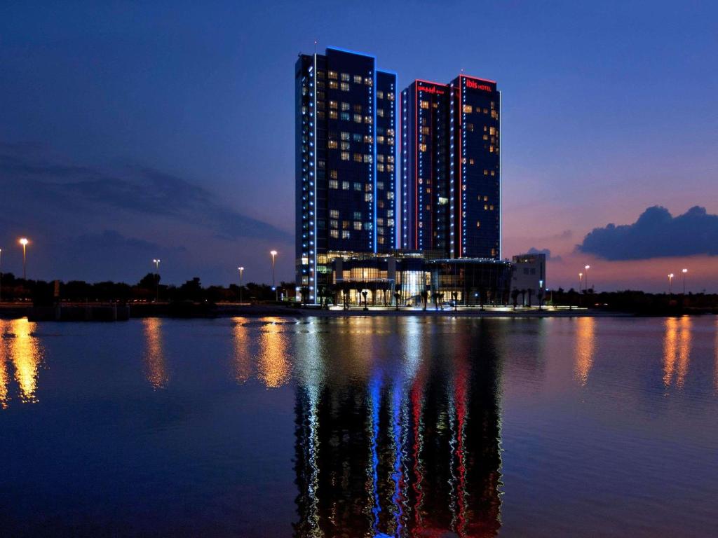 a large building on the water at night at Ibis Abu Dhabi Gate in Abu Dhabi