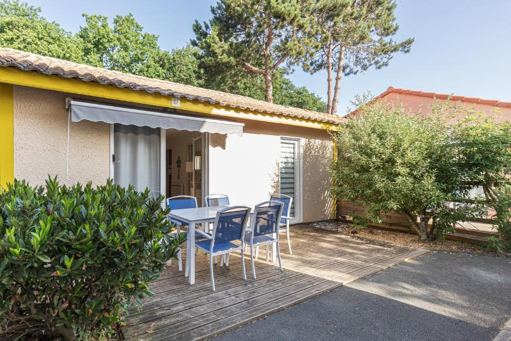 a deck with a table and chairs on a house at Villa du Lac - Conciergerieland in Soustons