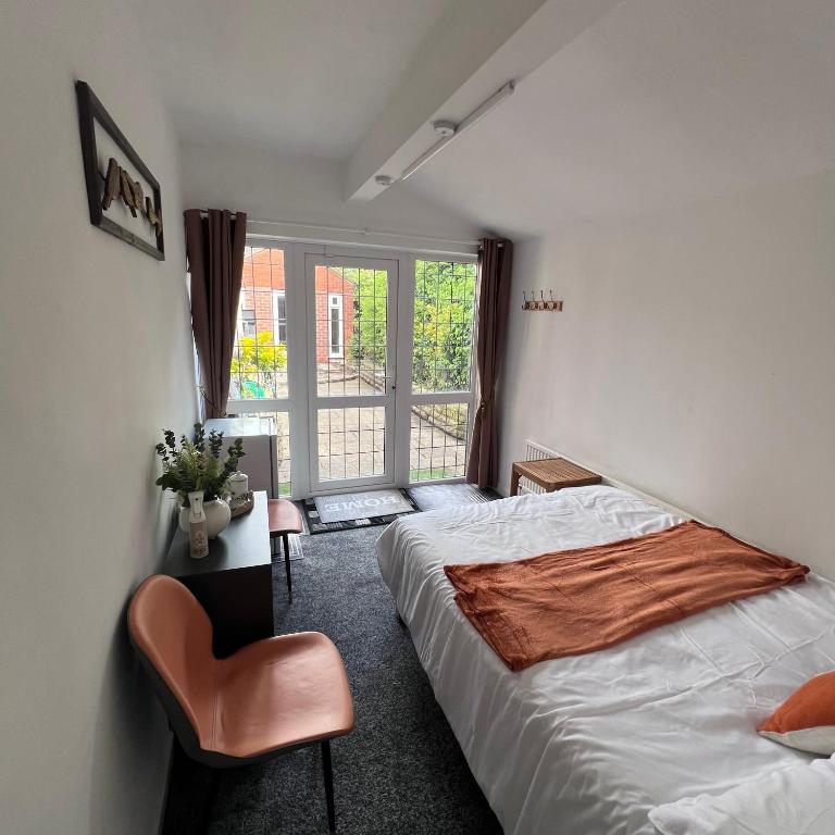 a bedroom with a bed and a chair and a window at Rizvi house in Moston