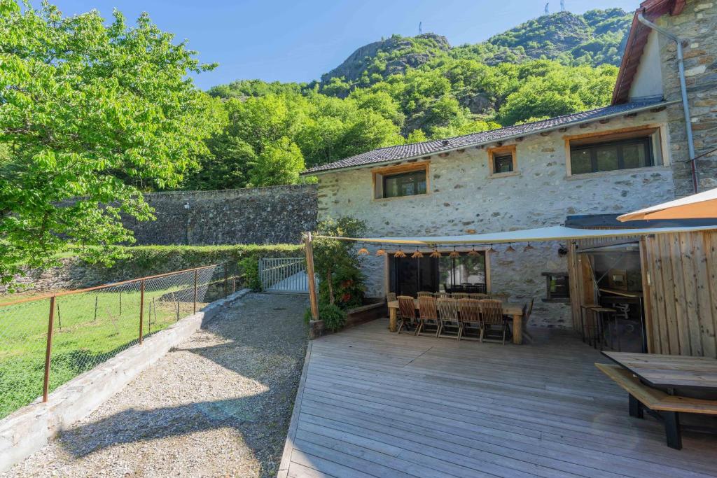 a house with a wooden deck with a table and chairs at Gite - La grange Tima in Orgeix