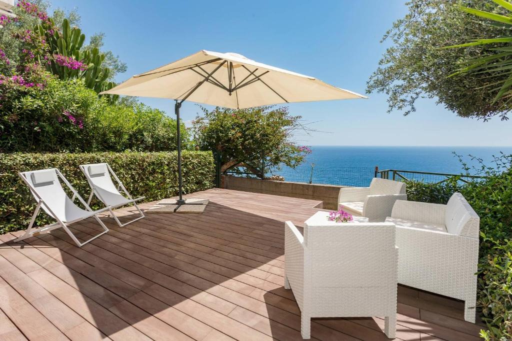 a patio with two chairs and an umbrella at Paradise Residence Garden in SantʼAlessio Siculo