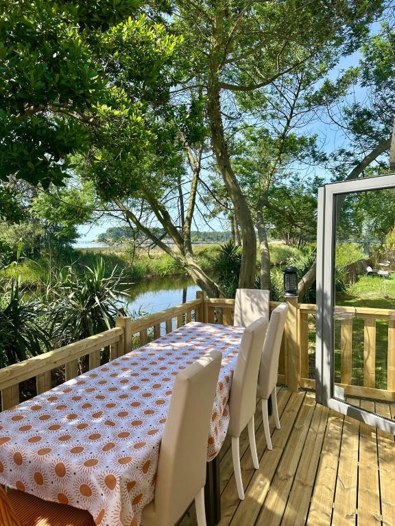 a table and chairs on a deck with a view of the water at Escapade in Lège-Cap-Ferret