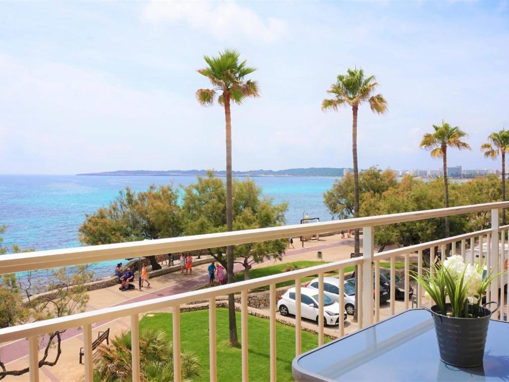 a balcony with a view of the ocean and palm trees at La perla del mar 1 in Son Servera