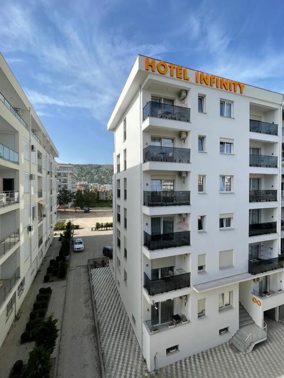 an apartment building with a hotel infinity sign on top at Hotel Infinity Shëngjin in Lezhë