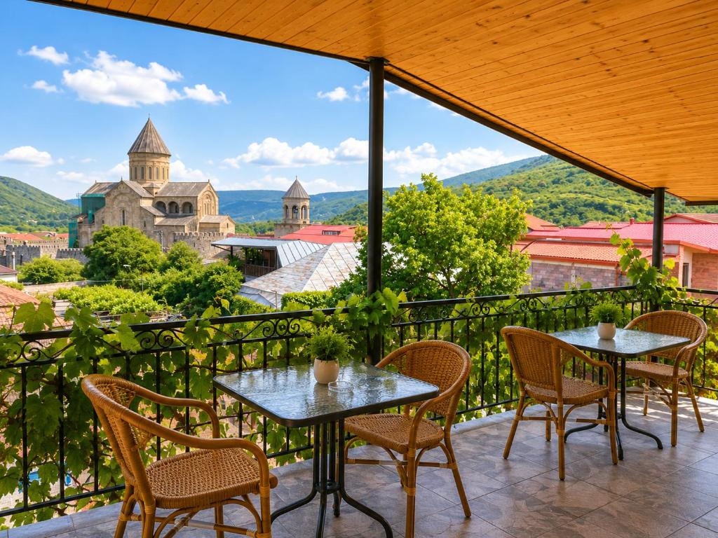 ein Balkon mit Tischen und Stühlen und Blick auf eine Burg in der Unterkunft Hotel Prime in Mzcheta