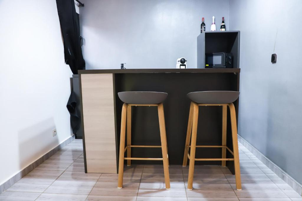 a kitchen with a black counter and two stools at Résidences AMAN in Morofé