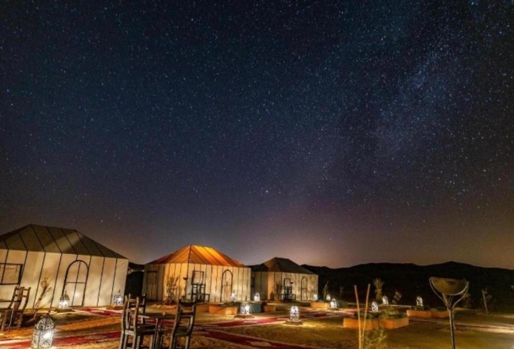 a cluster of buildings under a starry sky at night at Palace desert camp in Merzouga