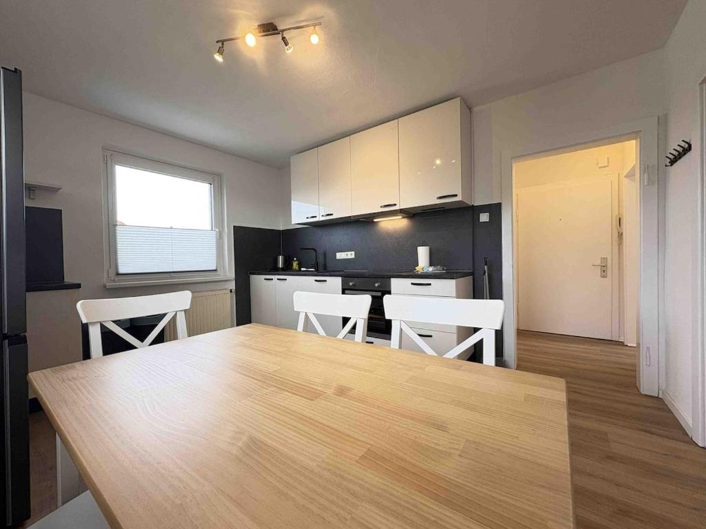 a kitchen with a large wooden table and white chairs at LEU111 komfortable Monteurwohnung in Leuchtenberg