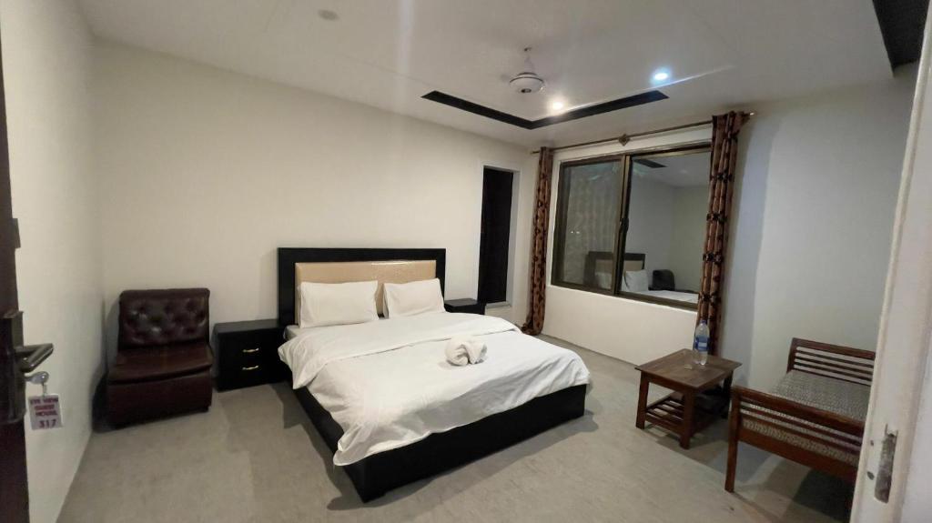 a bedroom with a bed and a chair and a window at EYE VIEW hotel skardu in Skardu