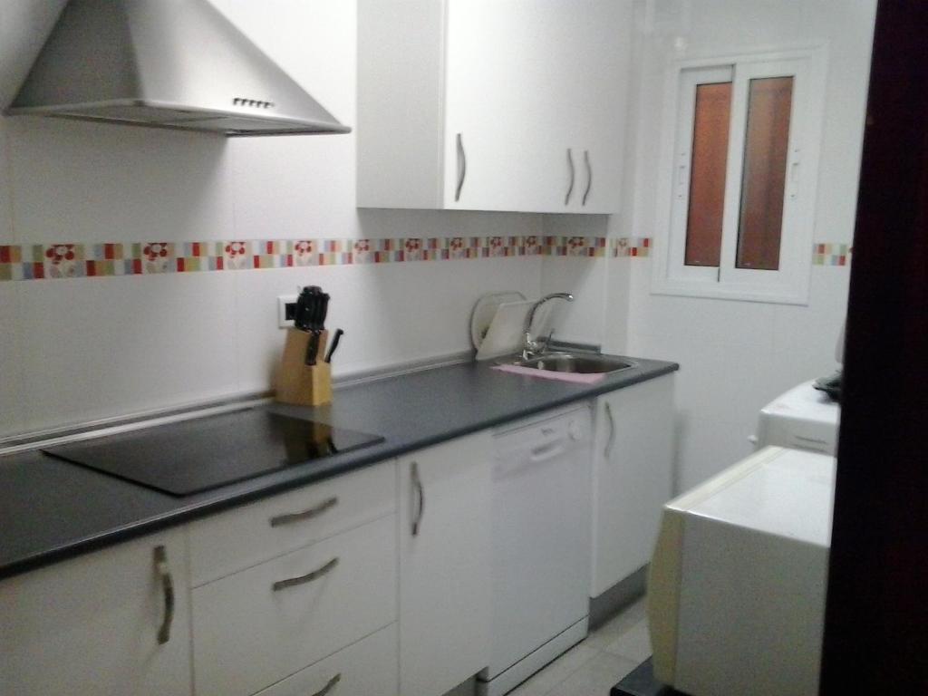 a kitchen with white cabinets and a sink at Apartamento Santo Tomás in Cádiz