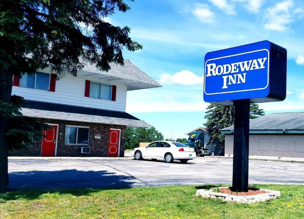 a blue road way inn sign in front of a building at Rodeway Inn Kalkaska in Kalkaska