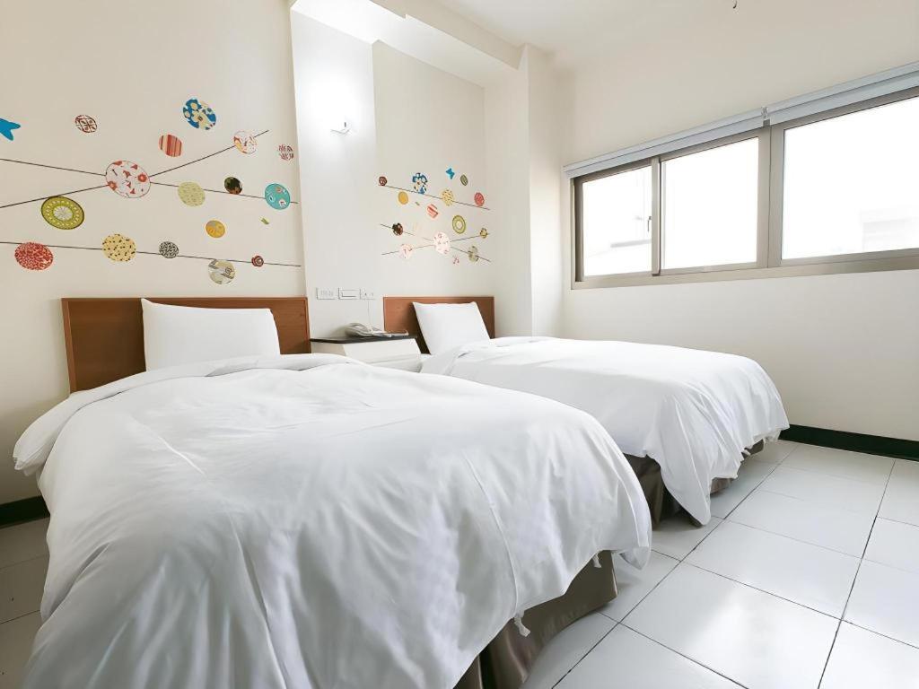 two beds in a room with white sheets at E Moon Hotel in Taichung