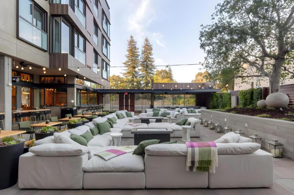 a patio with white couches and tables and a building at Park James in Menlo Park