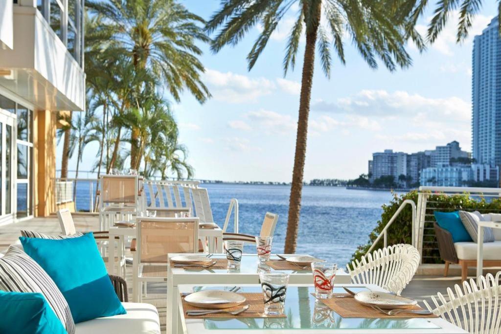 a patio with tables and chairs next to the water at Mandarin Oriental Miami in Miami