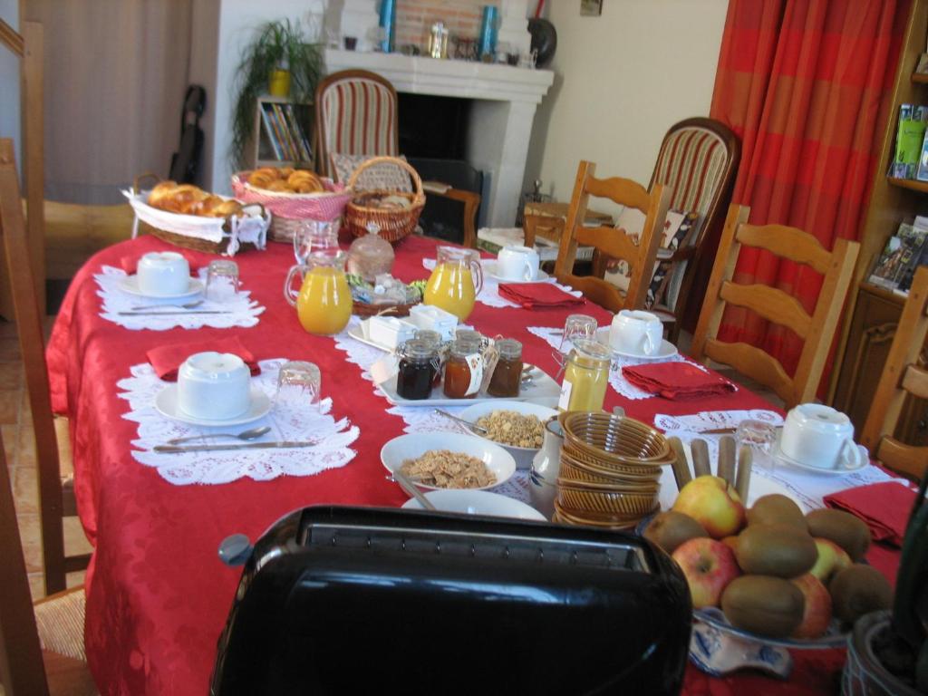 a table with a red table cloth with food on it at La Maison d'Héloïse in Pruillé